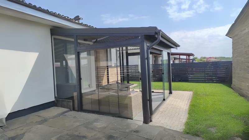 Terasă dotată cu sistem de închideri terase Gemini cu geamuri glisante din sticlă securizată de la Rom Decor